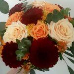 Bruidsboeket met rood, oranje en zalmkleurige bloemen.